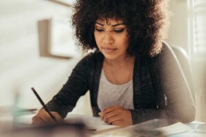 woman with curly hair writing while balancing work and home life in php